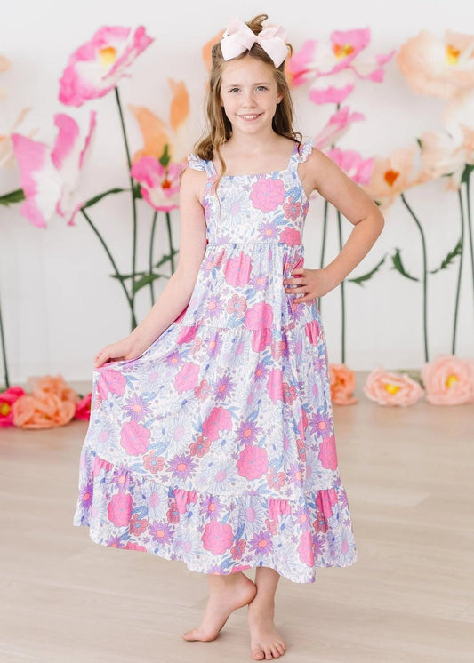 Young girl in a floral dress standing in front of a floral backdrop