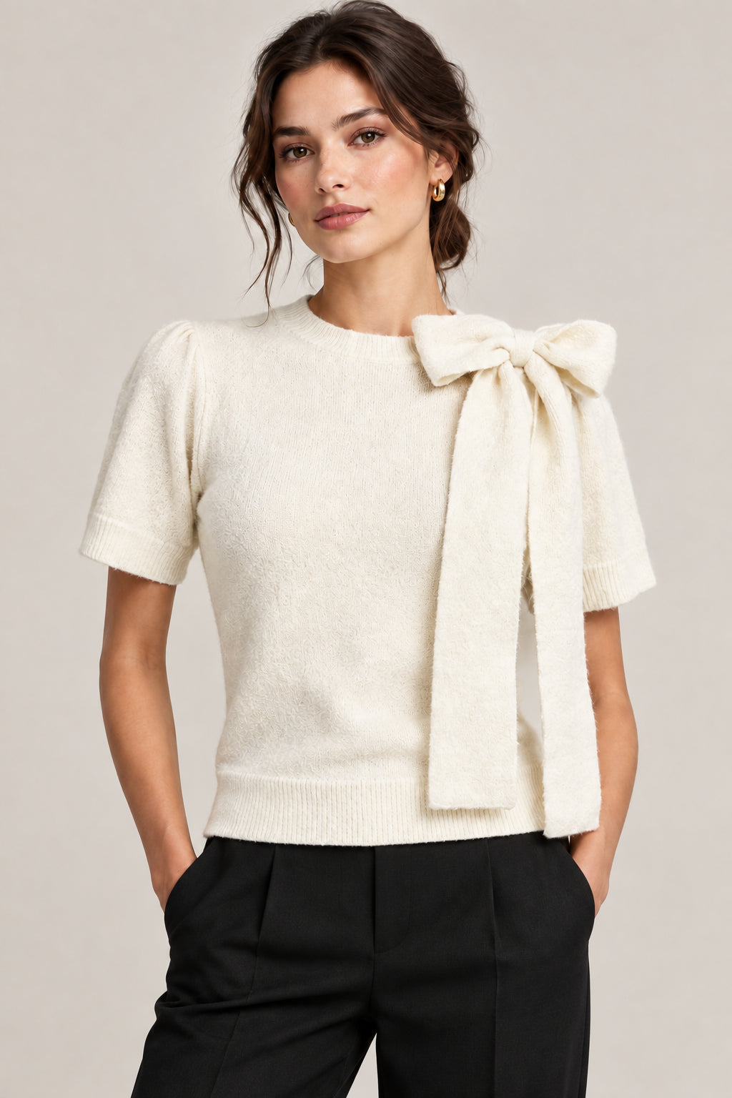 This ivory crew neck sweater features an elegant oversized tie neck bow and short puffed sleeves for a modern, feminine silhouette. Crafted from a breathable acrylic blend with plenty of stretch, it's designed for comfort and easy movement. Perfect for layering or wearing solo.