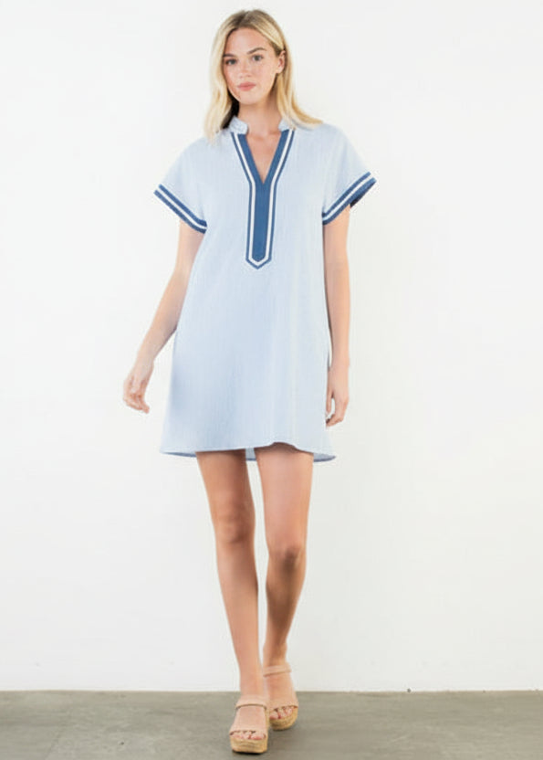 Woman wearing a light blue dress with blue trim on a white background