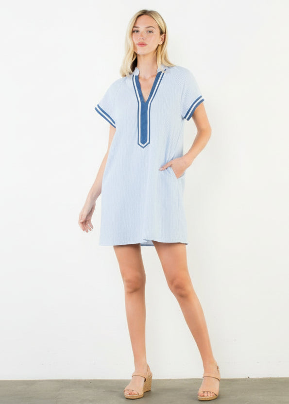 Woman wearing a light blue dress with blue trim against a white background
