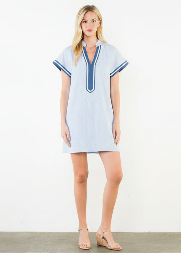 Woman wearing a light blue dress with blue trim on a white background