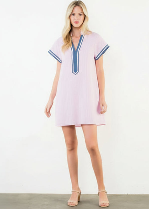 Woman wearing a pink dress with blue trim on a white background