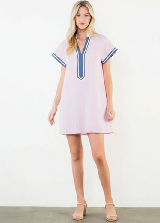 Woman wearing a pink dress with blue trim on a white background