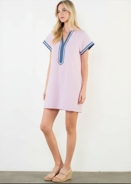 Woman wearing a pink dress with blue trim on a white background