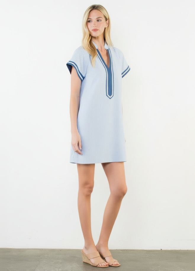 Woman wearing a light blue dress with white trim on a white background