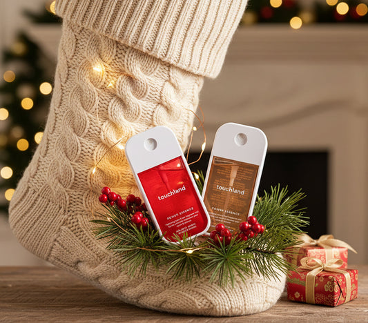 Two touchland power essence bottles, one red and one vanilla velvet, held in a hand.