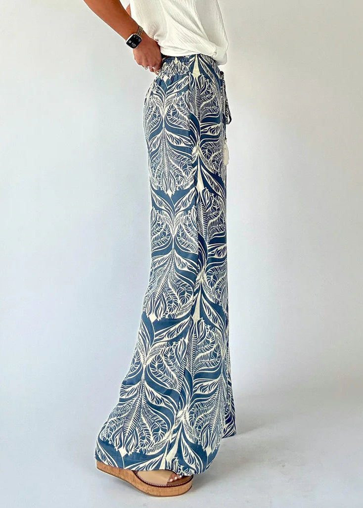 Person wearing blue and white leaf-patterned pants on a white background