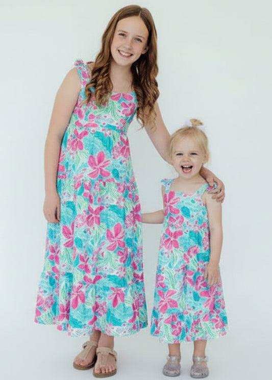 Two children wearing matching floral dresses on a white background