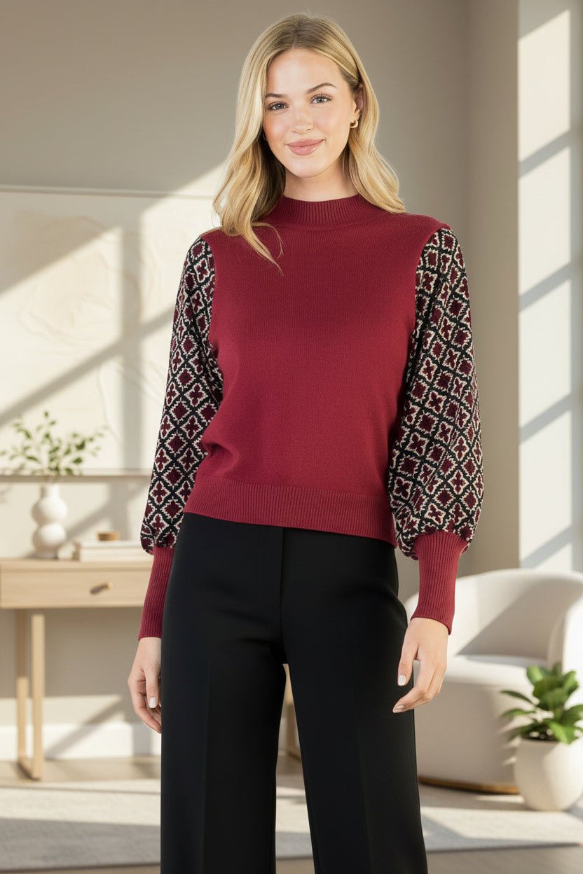 Woman wearing a maroon sweater with patterned sleeves on a white background