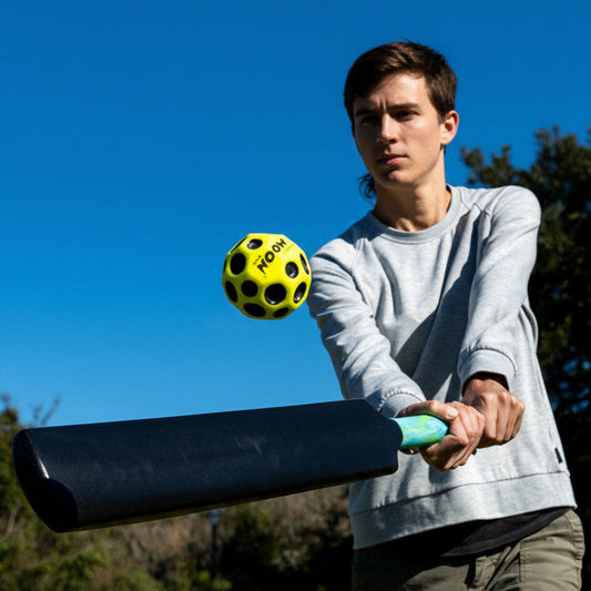 Person playing with a black and green pickleball on a clear day