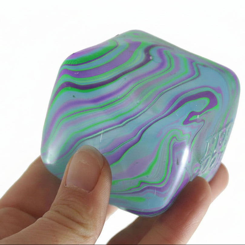Colorful marbled cube held in a hand with 'Curious Minds' branding.
