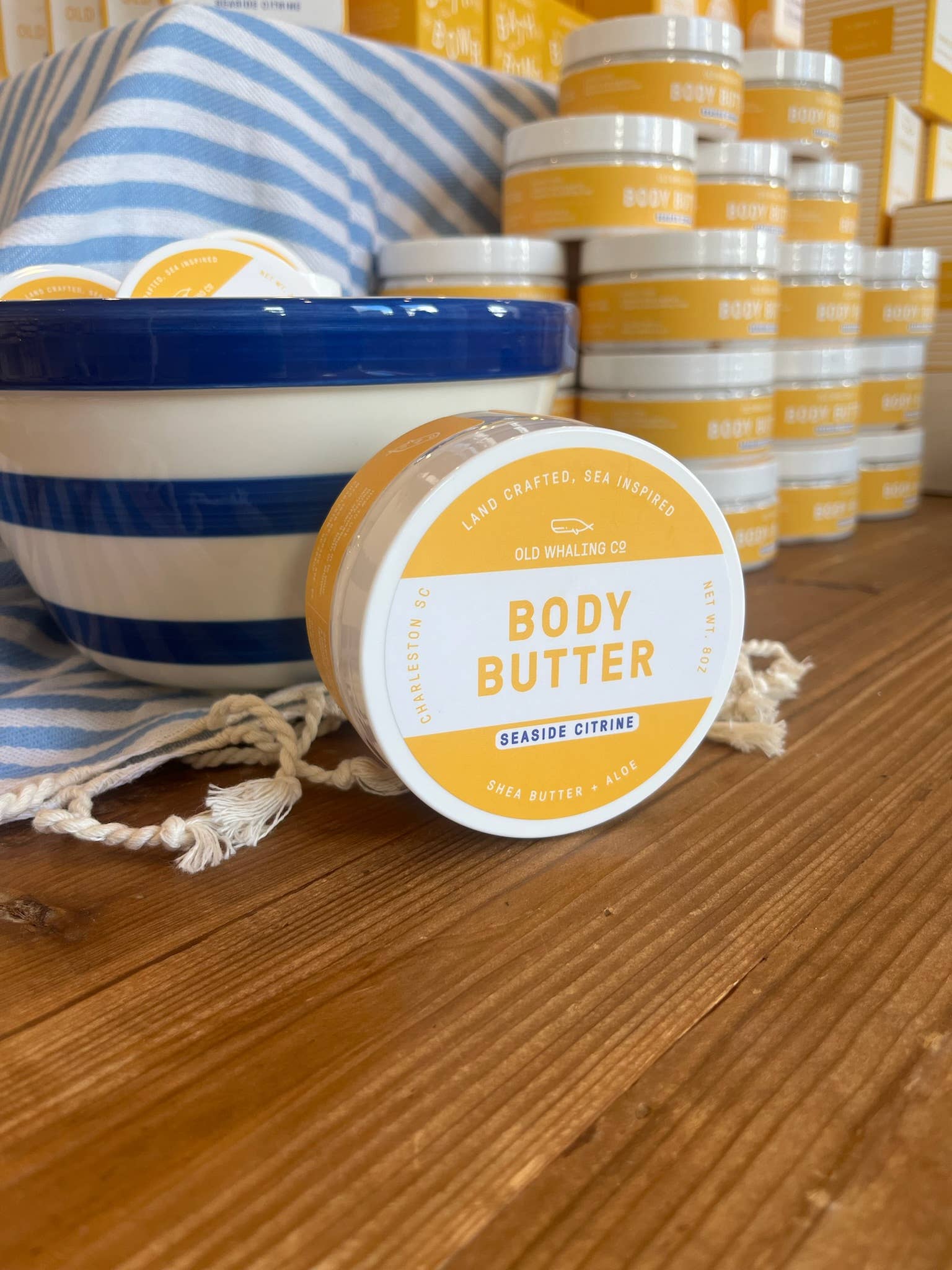 Body butter containers with a striped towel on a wooden surface