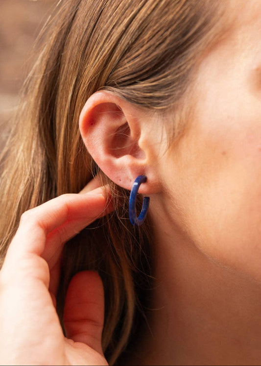 Close-up of a person wearing a blue hoop earring with a blurred background