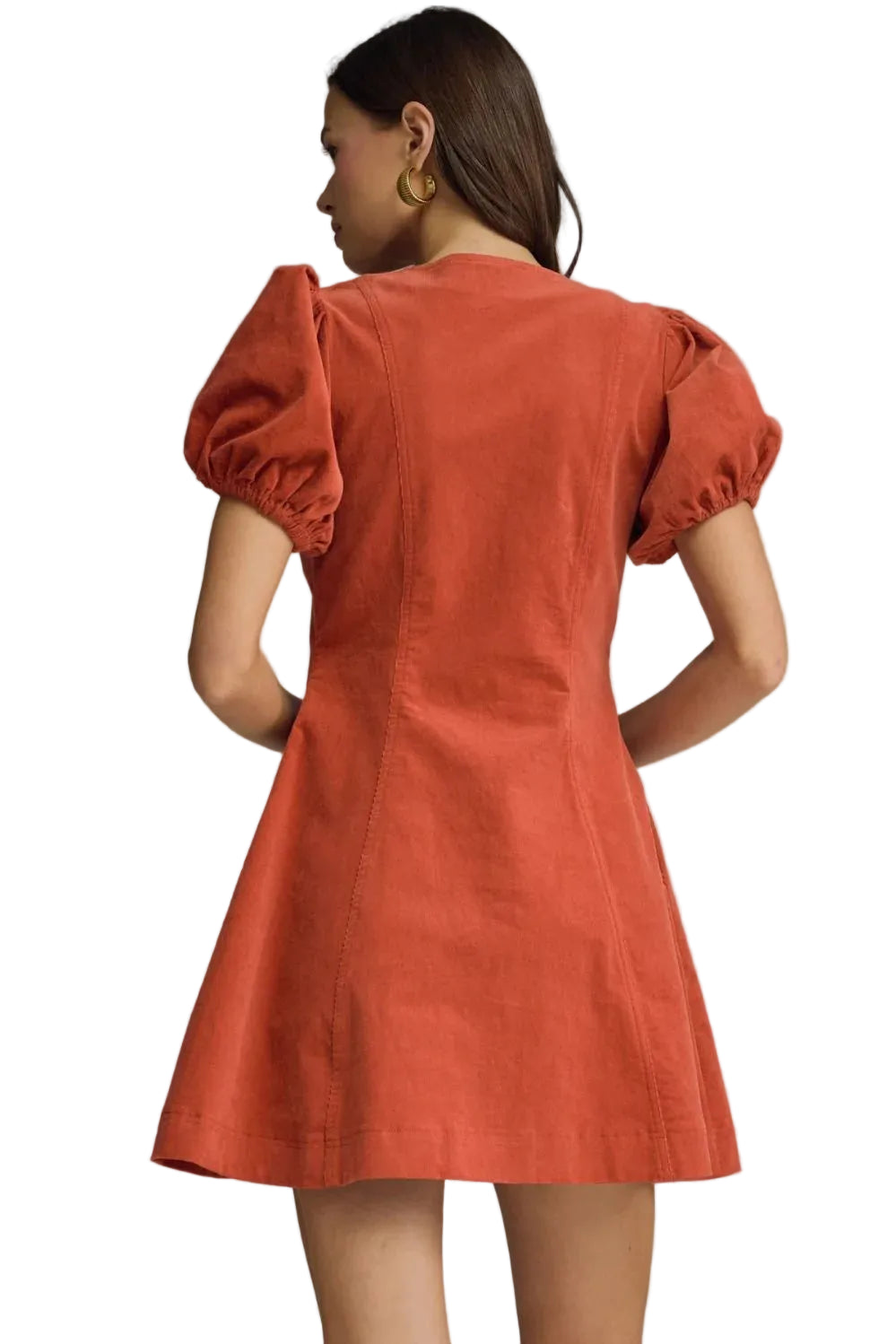 Woman wearing a rust-colored dress with puff sleeves against a gray background