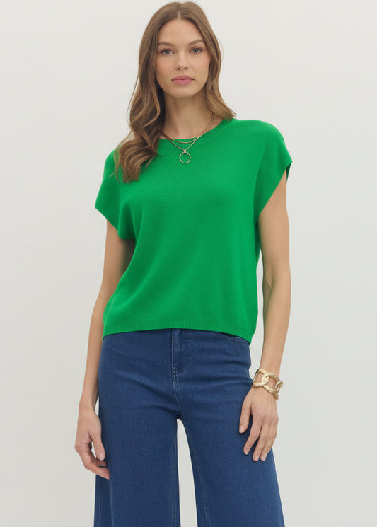 Woman wearing a green top and blue jeans on a plain background