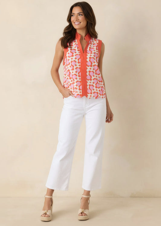 Woman wearing a colorful sleeveless top and white pants against a beige background