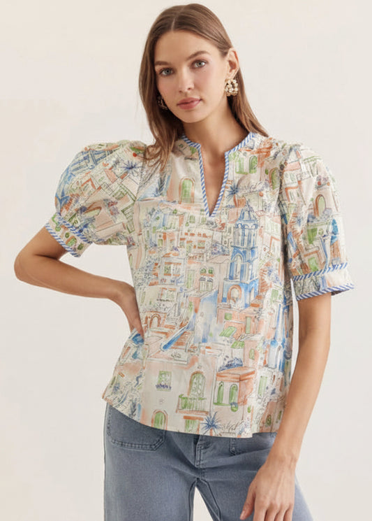 Woman wearing a colorful patterned blouse with short sleeves and blue jeans on a white background