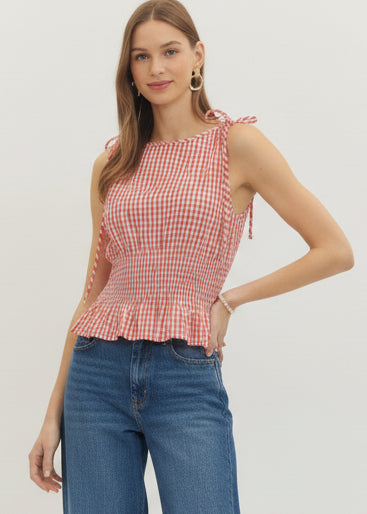 Woman wearing a red and white checkered top and white pants on a white background
