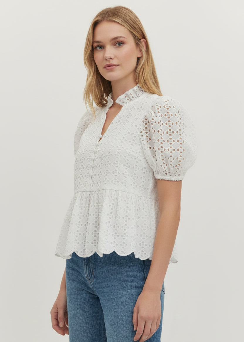 Woman wearing a white lace top and blue jeans on a plain background