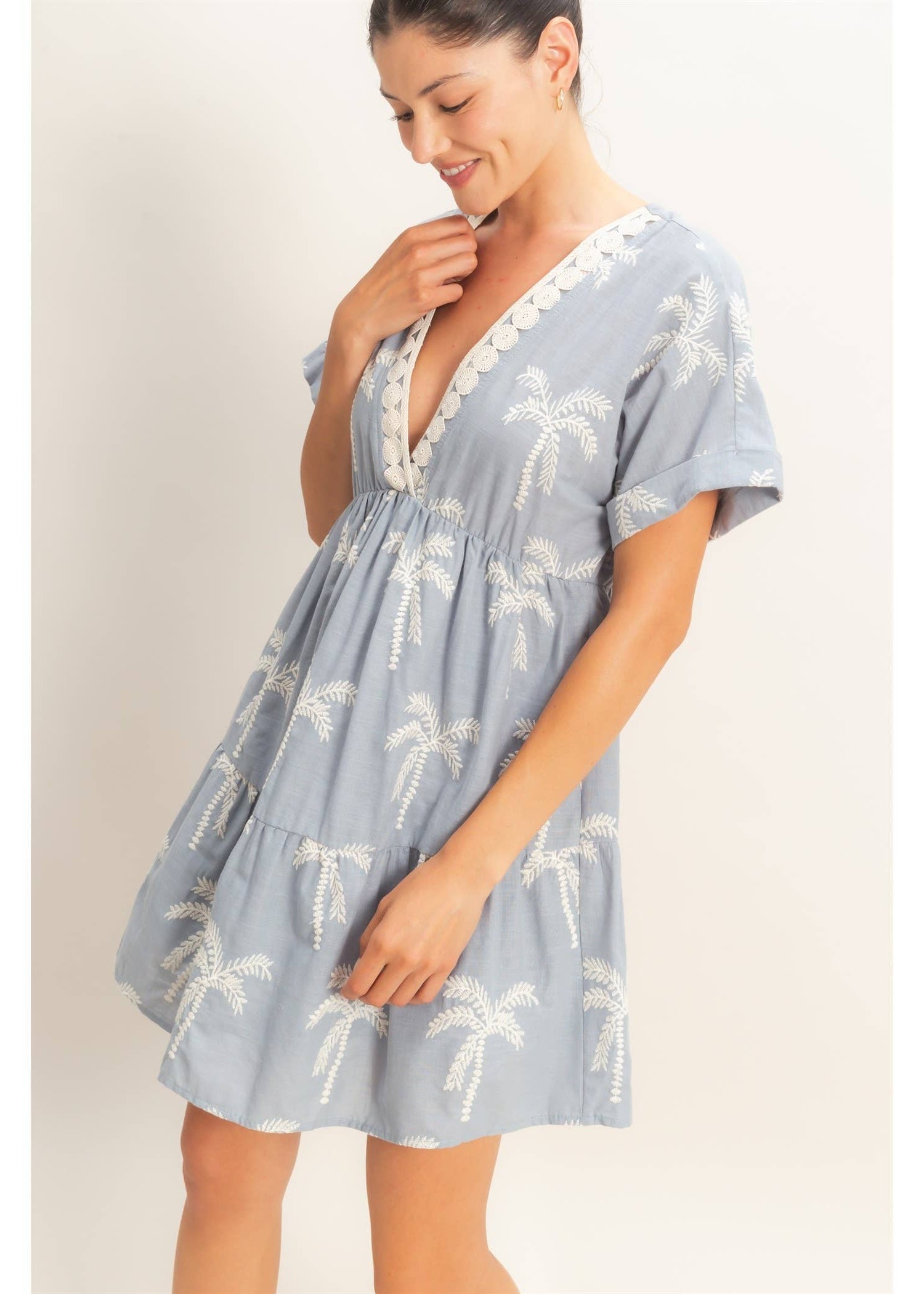 Woman wearing a blue dress with palm tree pattern on a plain background